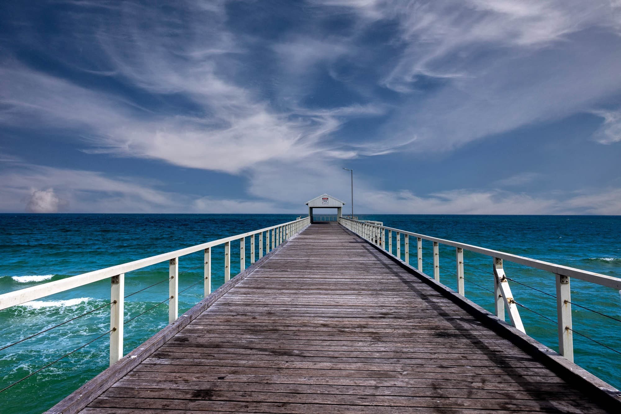 Pier leading to a sea shelter under a dramatic sky